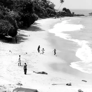 Boys playing football on sand beach