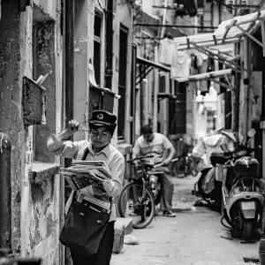 路地で配達する郵便配達の女性