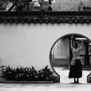 Woman standing in a hole in the wall of Yu Garden