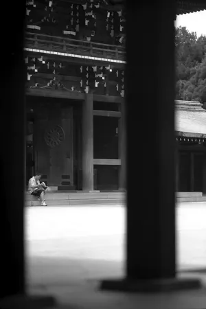Man sitting in front of gate in Meiji Jingu
