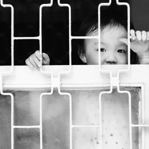 Boy looking through window lattice