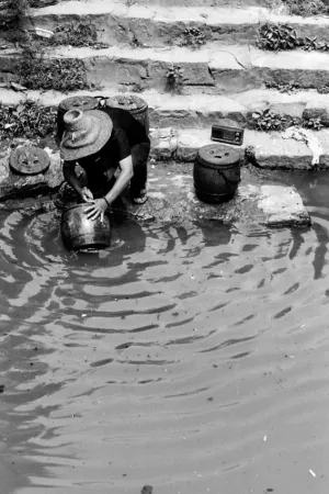 川の水で壺を洗う女性