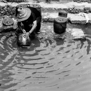 川の水で壺を洗う女性