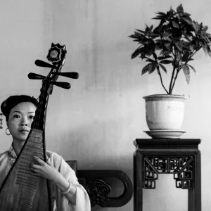 Woman playing Chinese lute with deadpan face