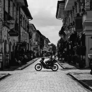 Silhouetted motorbike running stone paved street