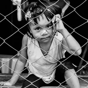 Girl sitting on the other side of wire netting