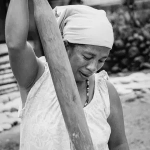 Woman milling rice with a wooden stick