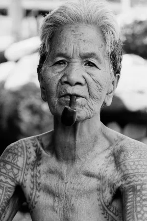 Tattooed older woman puffing on pipe