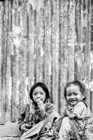 Two girls sitting in front of corrugated wall