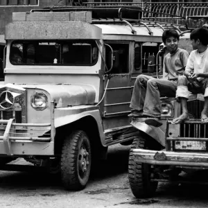 Two boys sitting on the hood of a jeepney