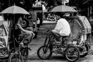Pedicab drivers chatting under umbrella
