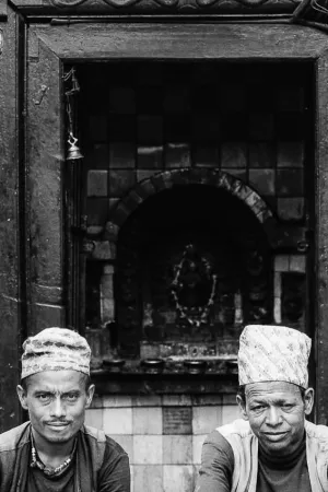 Two men sitting in front of small shrine