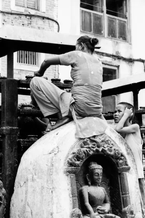 Woman sweeping while sitting on statue of Buddha