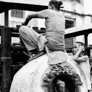 Woman sweeping while sitting on statue of Buddha
