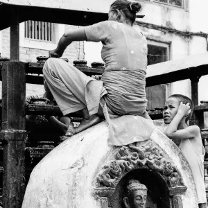 Woman sweeping while sitting on statue of Buddha