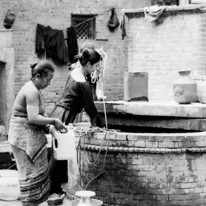 Women drawing water from well