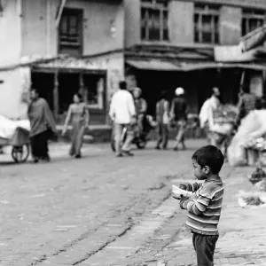 Shoeless boy standing alone by roadside