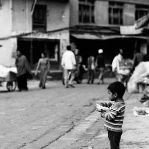 Shoeless boy standing alone by roadside