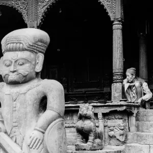 Man sitting behind stone statue