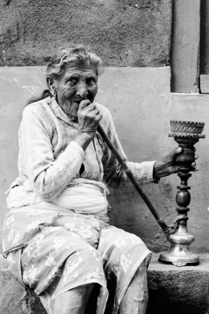 Older woman smoking water pipe under eaves