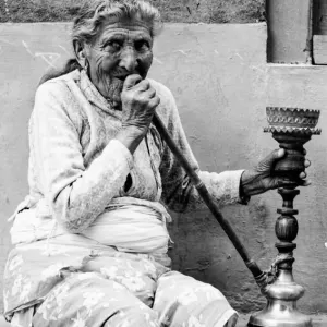 Older woman smoking water pipe under eaves