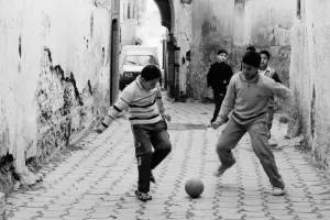 路地でサッカーをする男の子たち