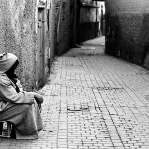 Woman sitting in an empty Marrakesh alley