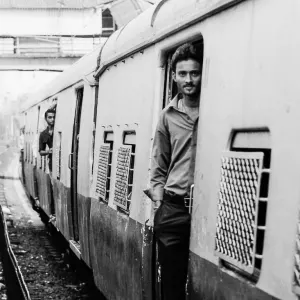 Man standing at the boarding gate of a running train