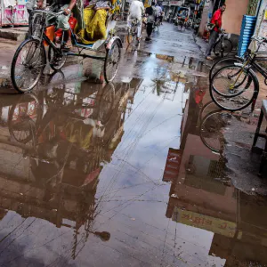 Cycle rickshaw going through a puddle