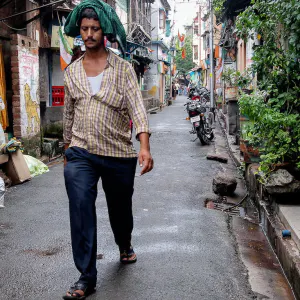 Man walking silently down an alley in a light rain