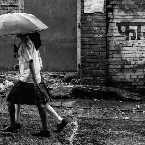 Two girls in rain with umbrella
