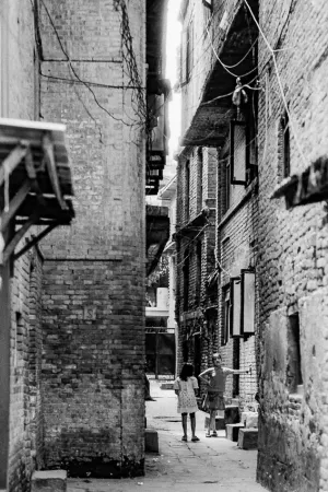 Girls standing talking in lane flanked by old brick buildings