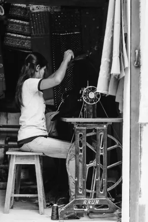 Woman sitting in front of sewing machine with a foot treadle