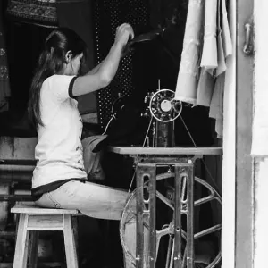 Woman sitting in front of sewing machine with a foot treadle