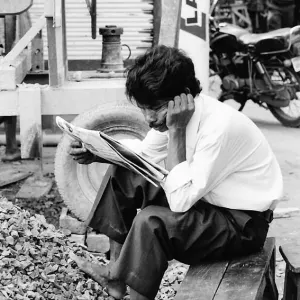shoeless man reading newspaper