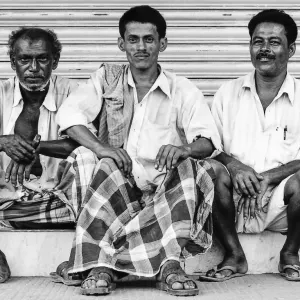 Three men sitting together in front of shutter