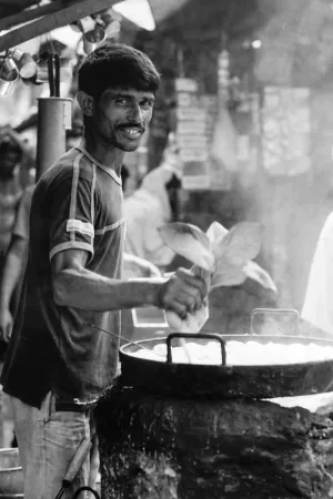 Man working in food stall with round pan