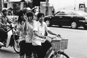 Three girls riding on same bicycle