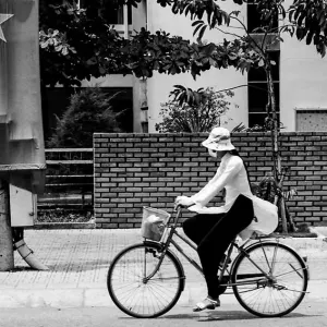道路脇に掲げられたベトナム国旗の前を通り過ぎる自転車