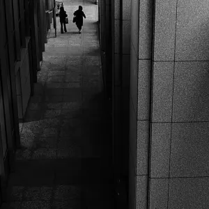 Two silhouetted figures walking in dim passage