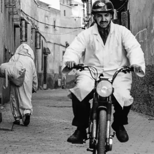 バイクに乗った白衣を着た男と路地を往くジュラバを着た男