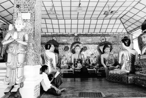 Man reading book beside Buddha images