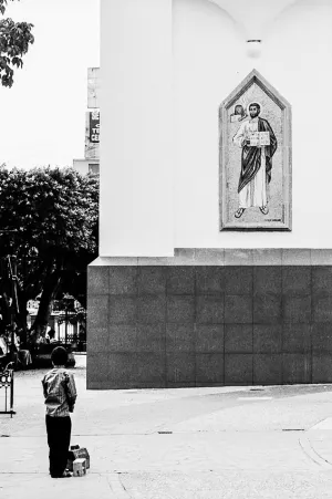 聖人の壁画の前に立つ男の子