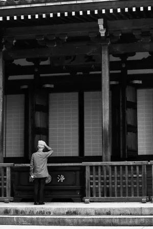 Man standiong in front of the main hall of Takahata Fudo